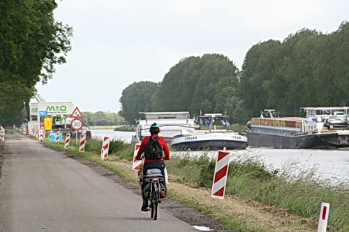 Twee forse binnenvaarders passeren elkaar, aan de westkant van de tijdelijke aanlegsteigers. Fietser op de voorgrond? Sieta Zijlstra uit Oldehove, bekende van school, die graag de harde wind trotseert.