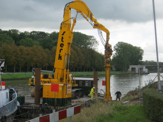 De drijvende hei-installatie van Sterk ramt de langwerpige ijzeren golfplaten de grond in. 