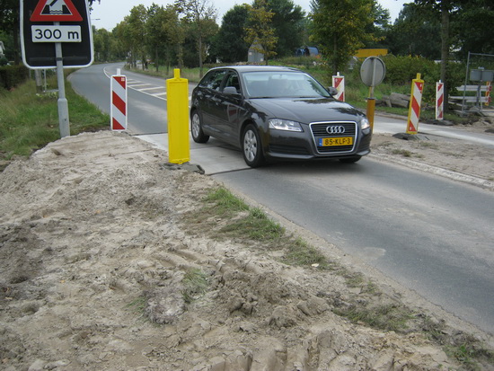 Hier zijn in het weekeinde rioleringsbuizen geplaatst. De weg is tijdelijk weer berijdbaar gemaakt door betonnen platen in het wegdek te plaatsen.
