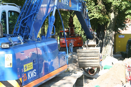 Bij de T-kruising van de Norritsstraat en de Noorderweg staan twee forse rupsvoertuigen te graven, pijpen en buizen te dragen, etc.  