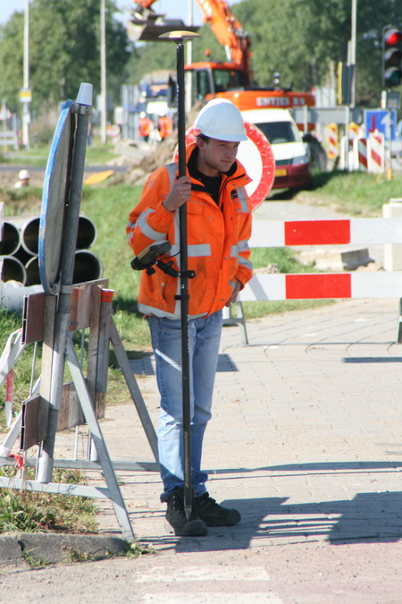 De GMBmedewerker nader beschouwd. Nee, die stok is niet om op te leunen.... Er zit een vernuftig apparaat aan, kost een paar centen....