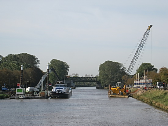 Verandering van onderwerp, wijziging van blikveld. Op de brug kijken naar de verzinkingsplaats, waar nog steeds wordt gebaggerd en geheid. Sterk aan het werk, maar ook in zijn werk? Te korte palen ijzeren balken en platen eruit, langere er weer in. Fout berekend? Mijn naam is haas....