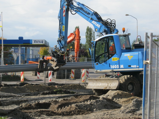 Bij het tunnelterrein wordt nog steeds intensief gewerkt. Hier een GMB-grijper die buizen transporteert. Riolering? Waterleiding?