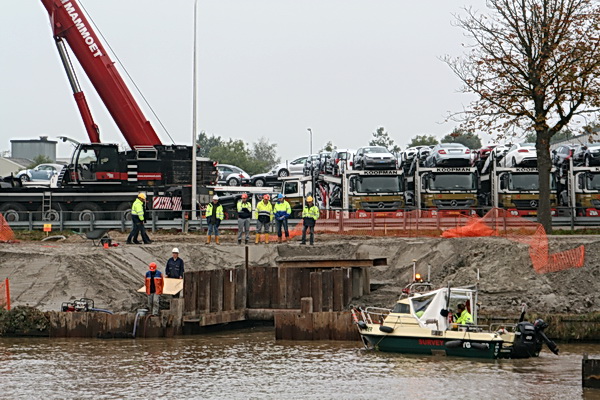 Aha, een volgende fase: Twee werklui komen aandragen met een brede 'vlonder', becommentarieerd door de melige nietsdoeners hogerop.....