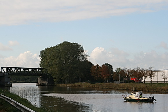Rustiek landschap met de oude spoorbrug op de achtergrond. "Hoe rustig glij-ijdt mijn bootje...." niet op het spieg'lend meer, maar op het water van het Van Starkenborghkanaal. De peilboot is even niet aan bod, in de wachtstand.
