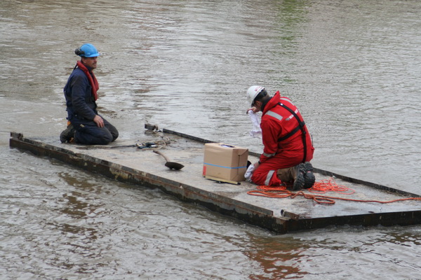 Twee werknemers die de tweelingbuizen gaan losmaken van Mammoetkraan en kraanschip "Redbad".