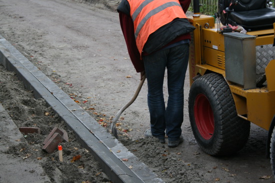 Heel zorgvuldig wordt het overbodige zand dat tegen de kantstenen ligt, verwijderd. 