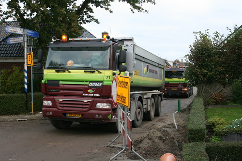 De ene vrachtwagen van Van der Wiel is zijn vrachtje al kwijt, kan de bak schoonmaken en wegrijden voor de volgende portie. De andere rijdt al weer voor de asfalteerders uit om de moderne machine te vullen met de grondstof die een mooie asfaltlaag oplevert...