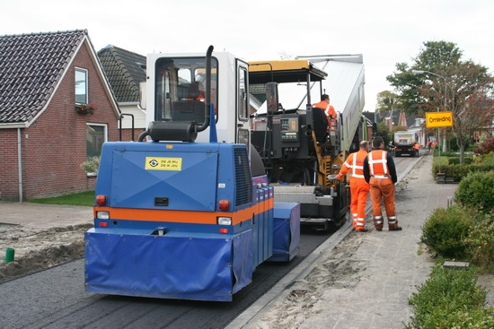 Achter de asfalteringsmachine volgt een solist op een ander apparaat die de laag verfijnd bewerkt. (Nee, het lijkt me geen stofzuiger....)