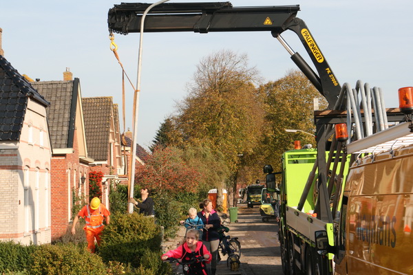 Even verderop, aan de westkant, wordt geprobeerd een nieuwe lantaarnpaal te plaatsen en aan te sluiten. Een ereboog voor passanten...